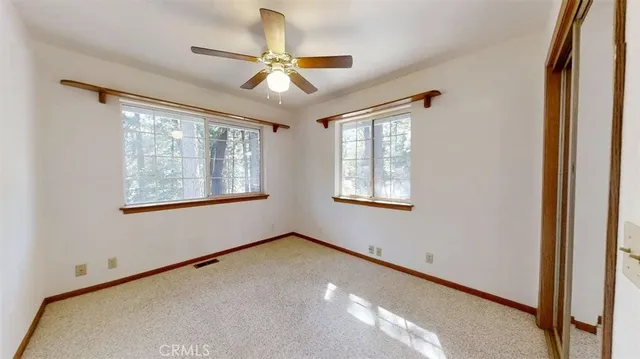 an empty room with windows and fan