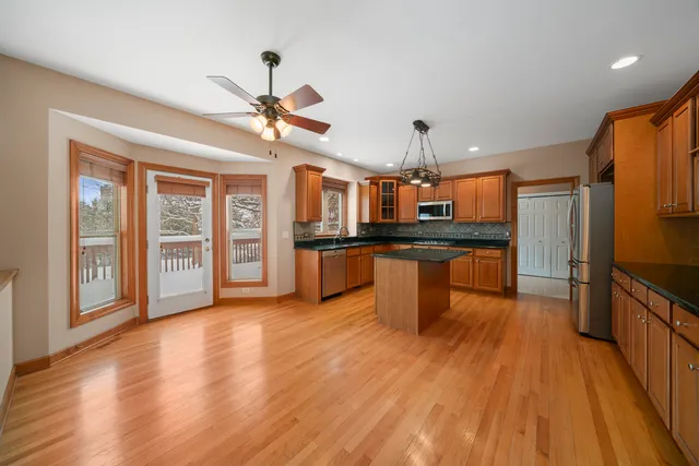 a kitchen with stainless steel appliances kitchen island granite countertop a stove top oven a sink and a refrigerator