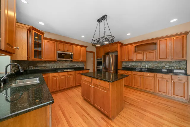 a kitchen with stainless steel appliances granite countertop a sink a stove top oven a counter space and cabinets