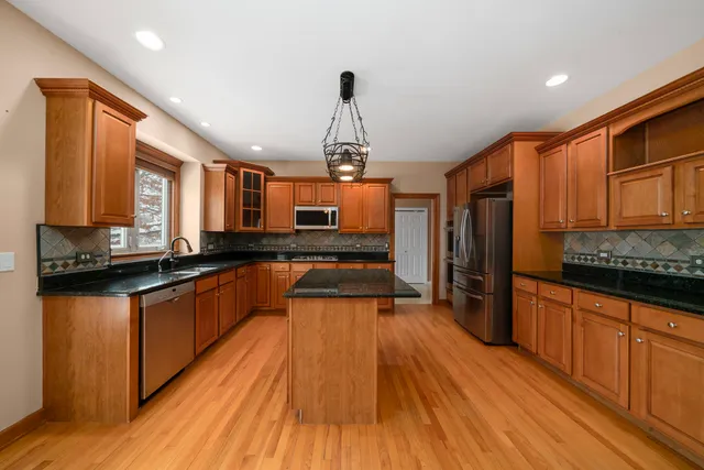 a large kitchen with granite countertop a large counter top space a sink stainless steel appliances and cabinets