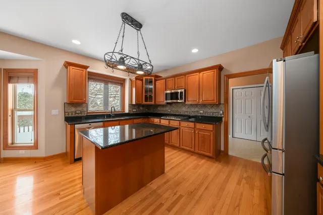 a kitchen with stainless steel appliances granite countertop wooden floors granite counter tops and a window