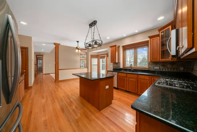 a kitchen with stainless steel appliances granite countertop a stove a refrigerator a sink dishwasher and wooden cabinets with wooden floor