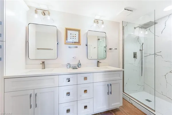 a bathroom with a double vanity sink mirror and shower