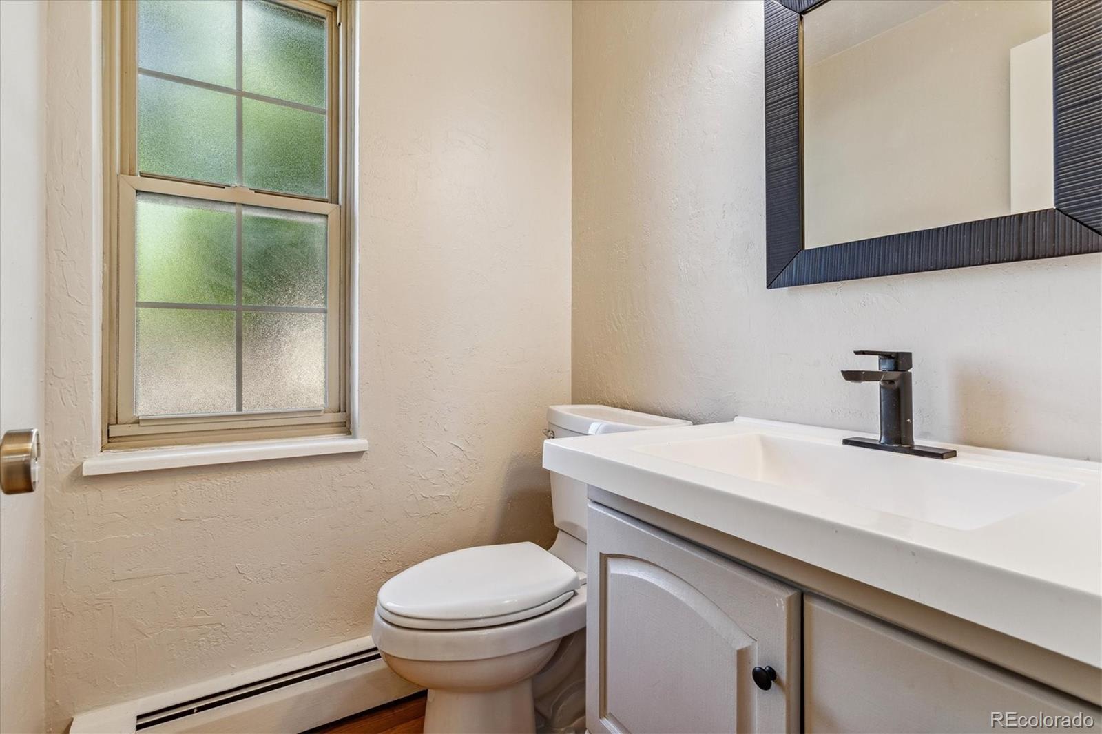 1975 South Locust Street Denver, CO 80224 - Photo 22 of 40 a bathroom with a sink a toilet and mirror