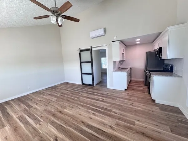 a view of empty room with wooden floor and fan