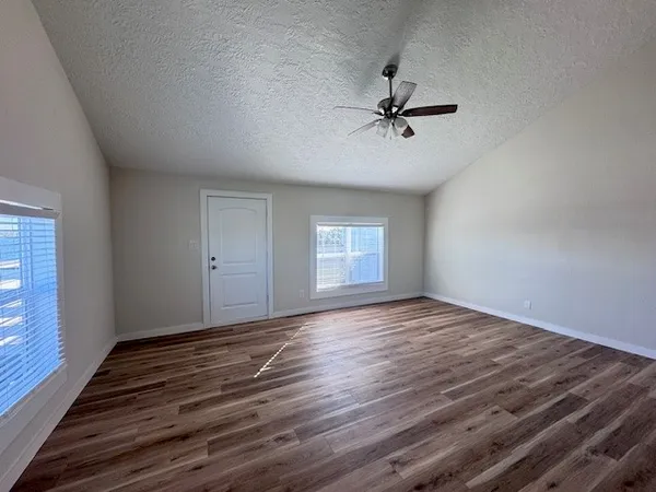 a view of empty room with wooden floor and window