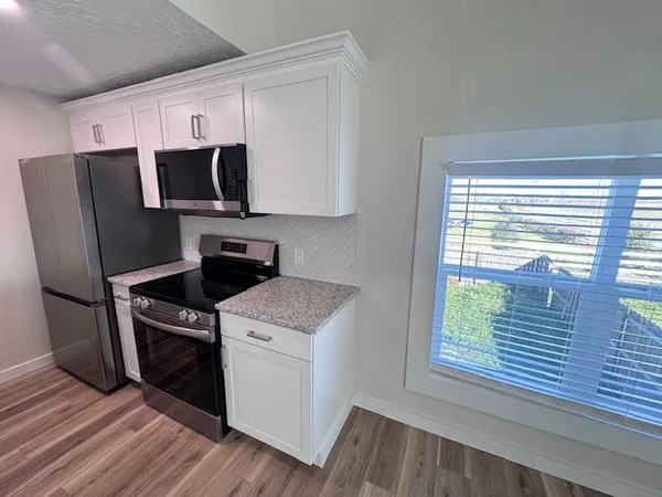 a kitchen with wooden floor sink and refrigerator