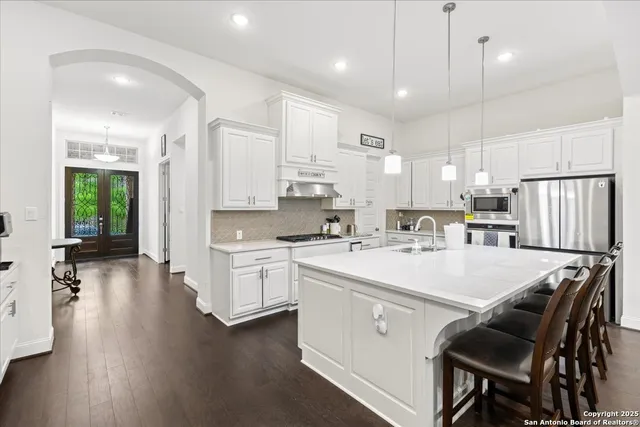 a large white kitchen with lots of counter space a sink appliances and cabinets