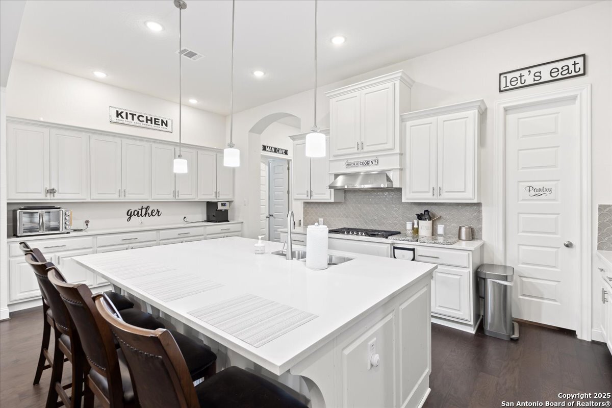 6957 Hallie Loop Schertz, TX 78154 - Photo 13 of 51 a kitchen with stainless steel appliances granite countertop a sink a stove a refrigerator and white cabinets with wooden floor