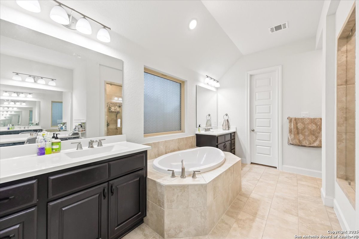 6957 Hallie Loop Schertz, TX 78154 - Photo 25 of 51 a bathroom with a tub sink and mirror