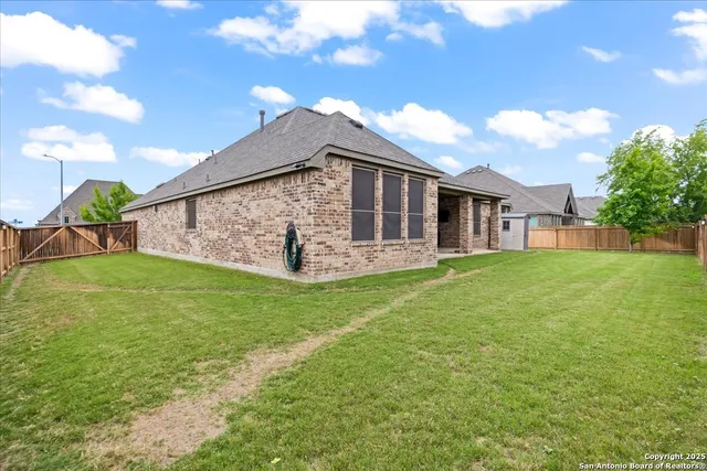 a backyard of a house with plants and large tree