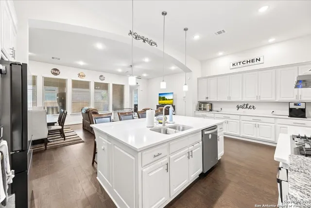a large white kitchen with a kitchen island a sink appliances and a counter top space
