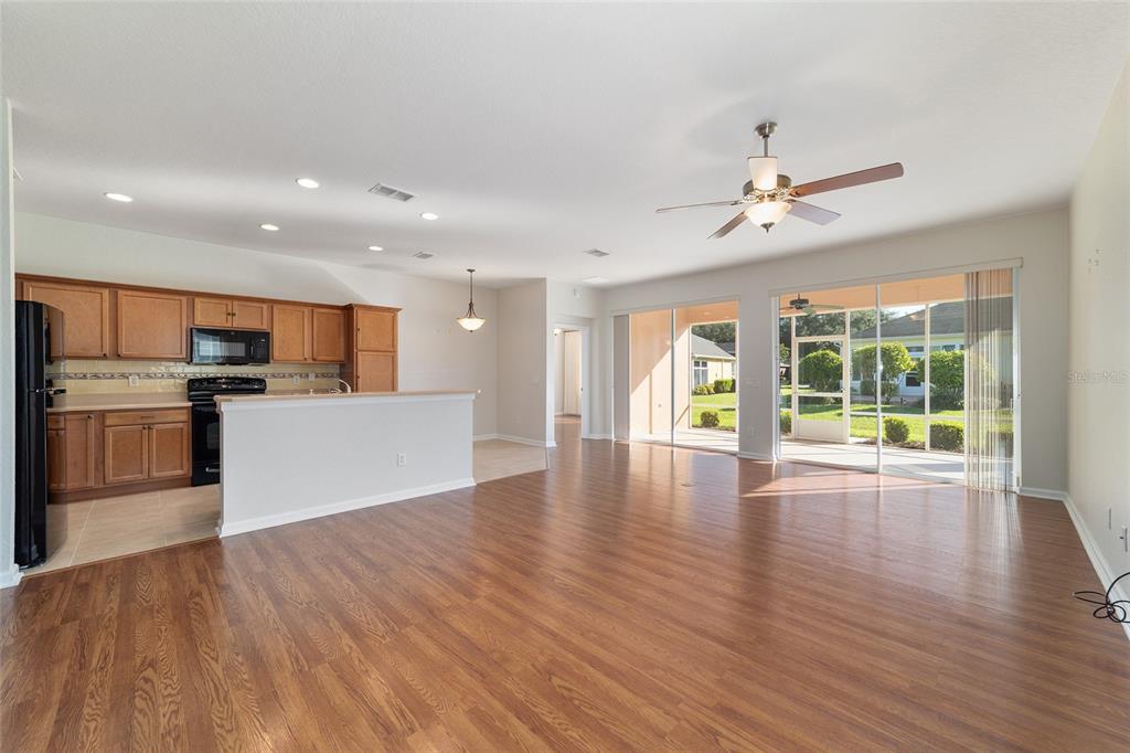 7153 Southwest 93rd Avenue Ocala, FL 34481 - Photo 13 of 61 a view of an empty room with wooden floor and a kitchen