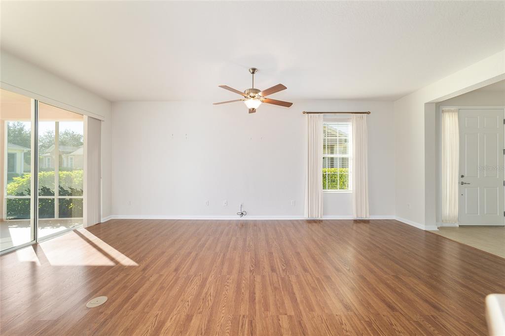7153 Southwest 93rd Avenue Ocala, FL 34481 - Photo 17 of 61 an empty room with wooden floor chandelier fan and windows
