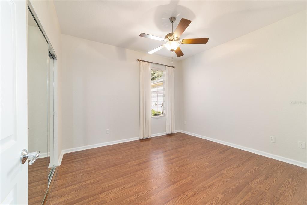7153 Southwest 93rd Avenue Ocala, FL 34481 - Photo 37 of 61 a view of an empty room with wooden floor and a ceiling fan