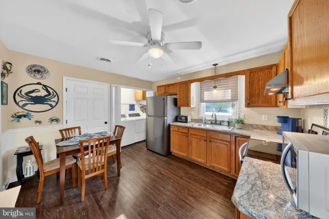 a kitchen with stainless steel appliances granite countertop a stove top oven a sink a dining table and chairs with wooden floor