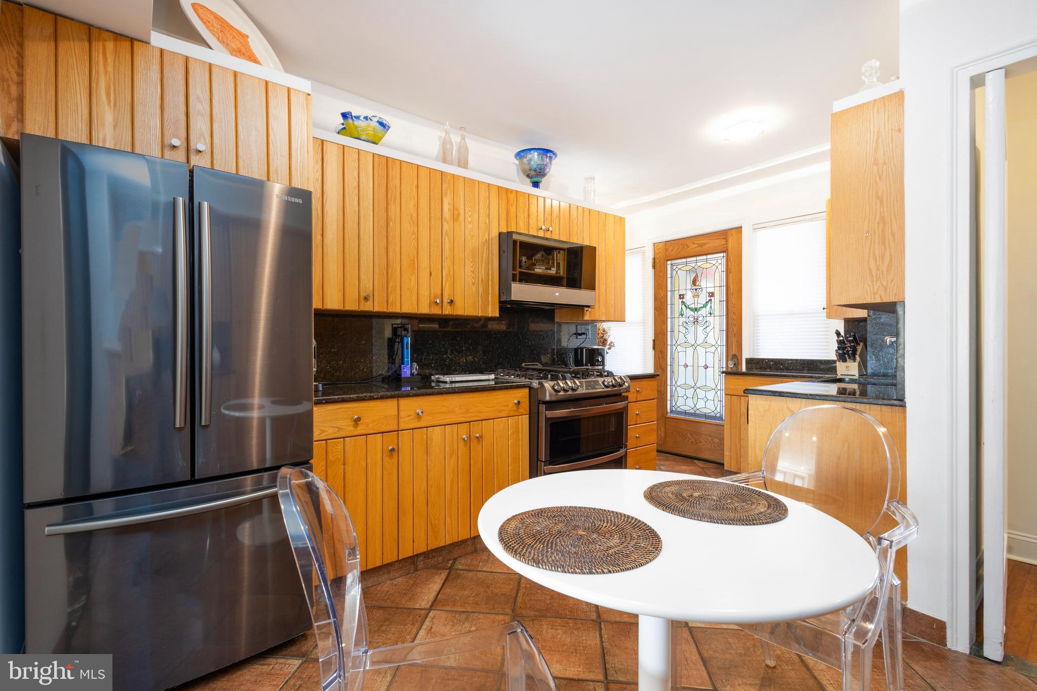 1901 Walnut Street, Unit 15B Philadelphia, PA 19103 - Photo 12 of 36 a kitchen with stainless steel appliances granite countertop a refrigerator a stove a sink a dining table and chairs with wooden floor