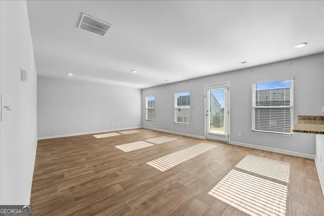 a view of an empty room with a window and wooden floor