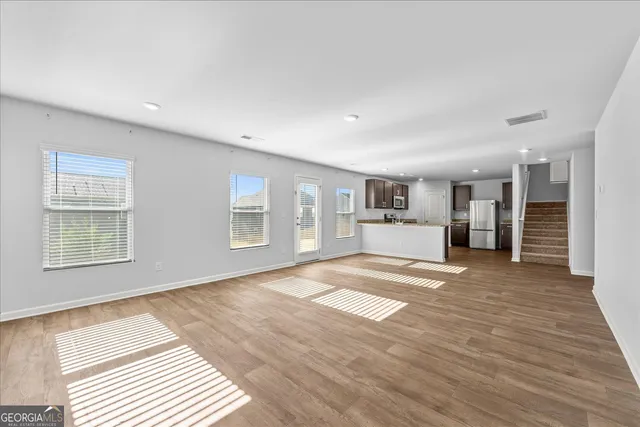 a view of an empty room with kitchen and a window