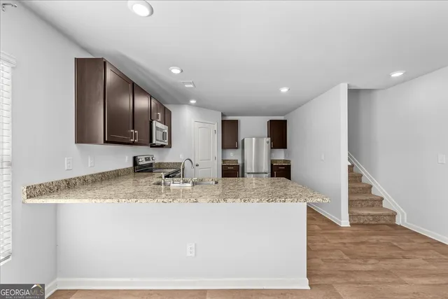 a view of a kitchen with kitchen island a sink stainless steel appliances and cabinets