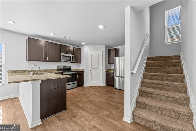 a large kitchen with wooden floor and stainless steel appliances