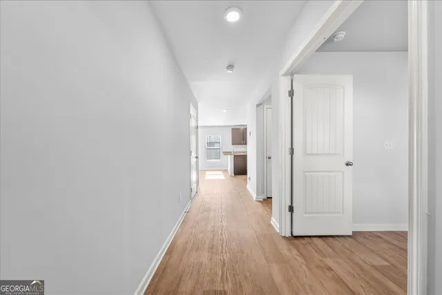 a view of a hallway with wooden floor and a bathroom