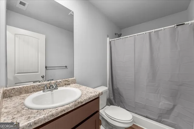 a bathroom with a granite countertop sink toilet and a mirror