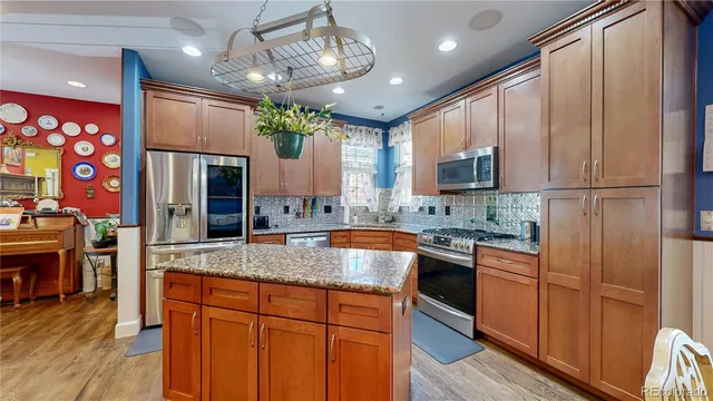 a living room with stainless steel appliances kitchen island granite countertop furniture a fireplace a rug and a chandelier