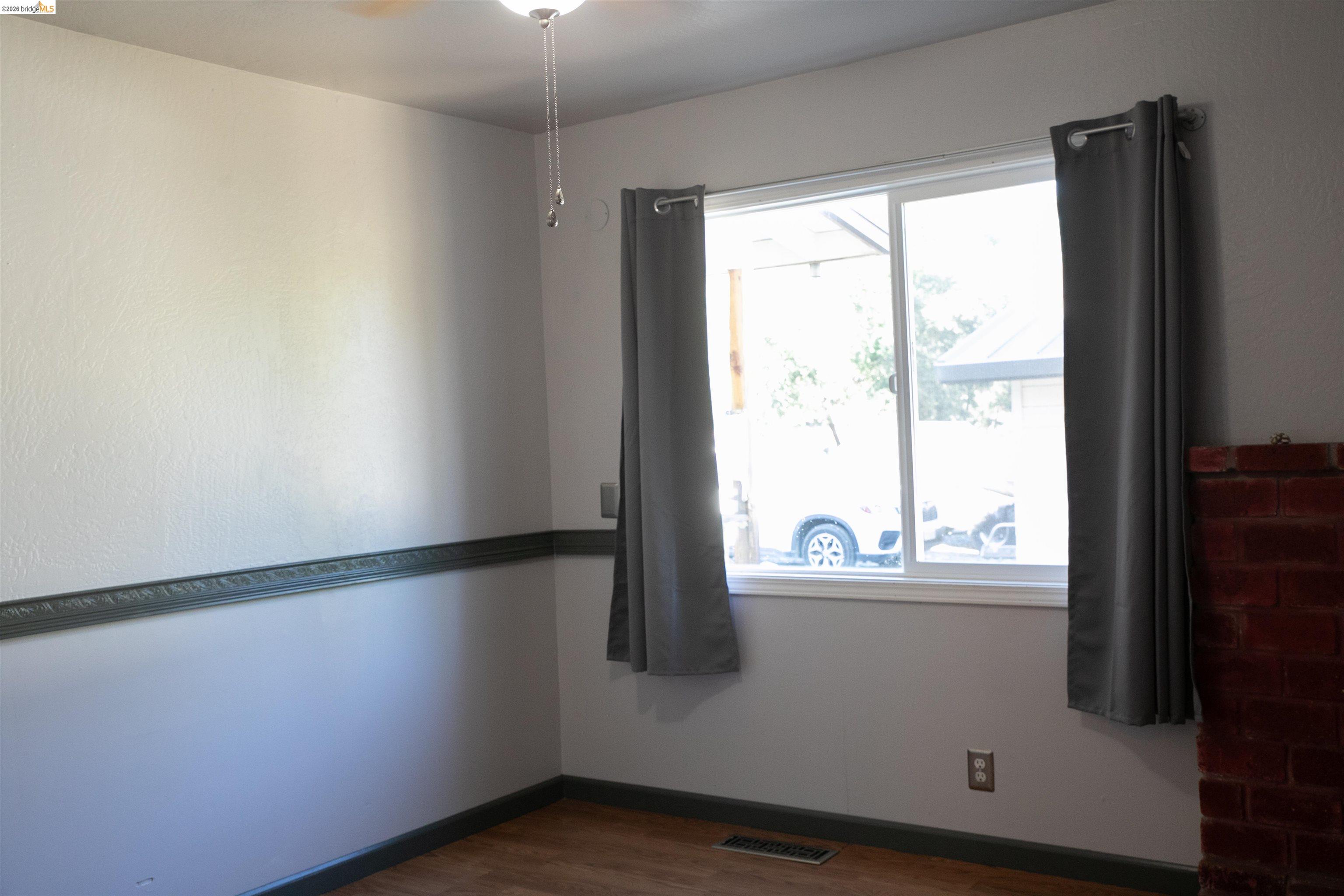 20982 Shaws Flat Road Sonora, CA 95370 - Photo 16 of 26 Light-filled room featuring a dual-pane window, wood-finish flooring, and a brick fireplace