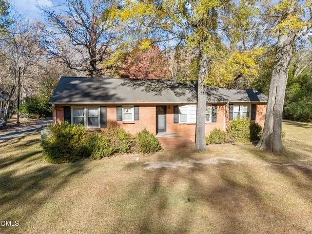 a view of a house with a yard and large tree