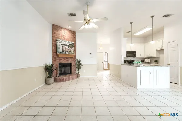 a large white kitchen with cabinets a sink a counter and a fireplace