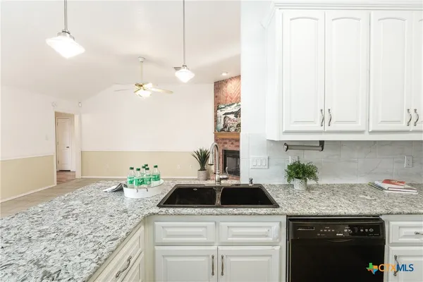 a kitchen with granite countertop a sink a stove and cabinets