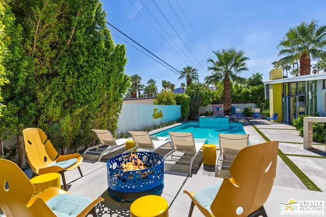 a view of a swimming pool with chairs and table in a patio