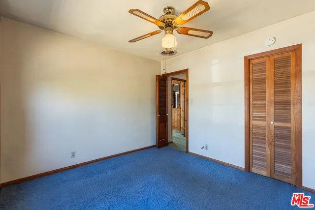 an empty room with closet and a chandelier fan