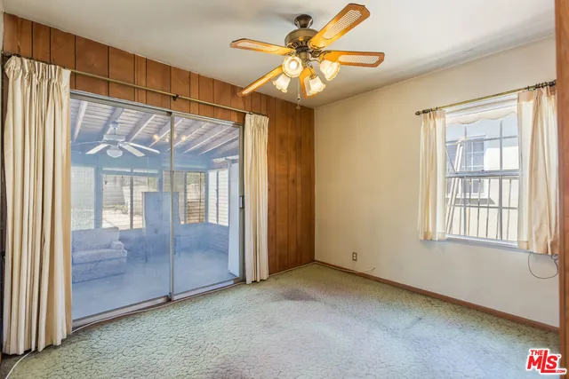 an empty room with windows and fan