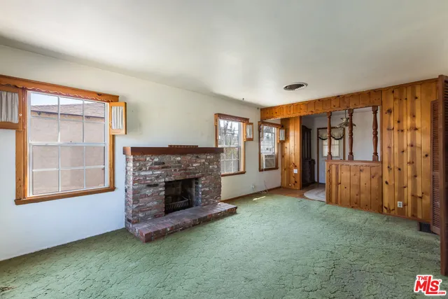 an empty room with windows and fireplace