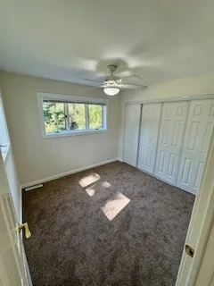an empty room with windows and fan