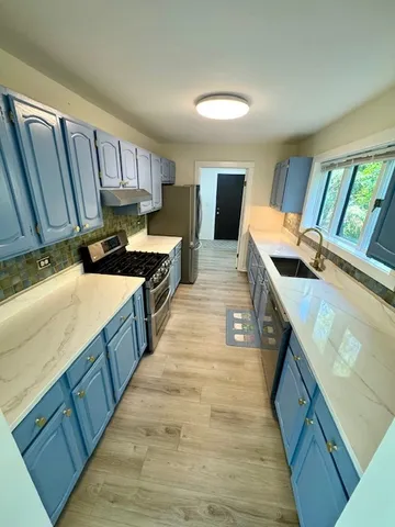 a kitchen with wooden cabinets a sink a stove and wooden floor