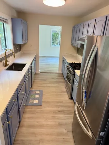 a kitchen with granite countertop a sink a counter top space stainless steel appliances and cabinets