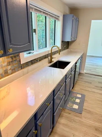 a kitchen with stainless steel appliances a sink window and wooden floor