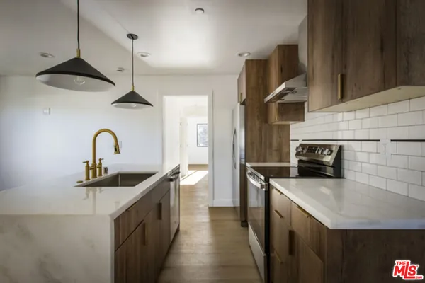 a kitchen with stainless steel appliances a sink a stove and a refrigerator with wooden floor