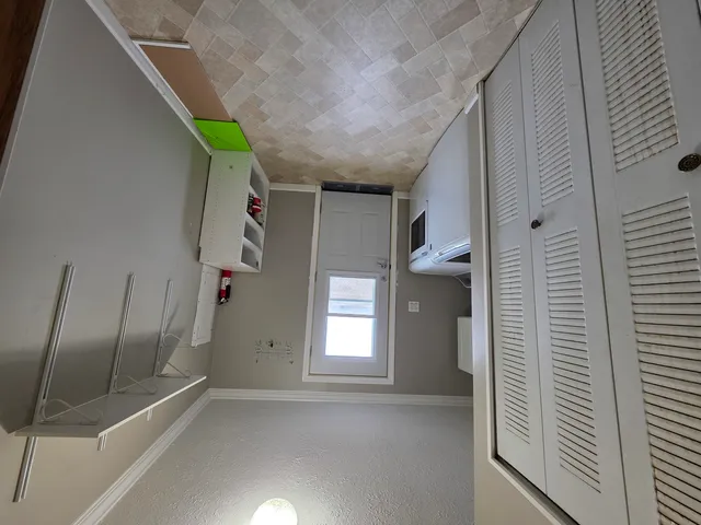 an empty room with windows fireplace and a ceiling fan