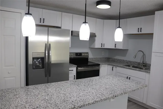 a kitchen with stainless steel appliances granite countertop a sink refrigerator and microwave