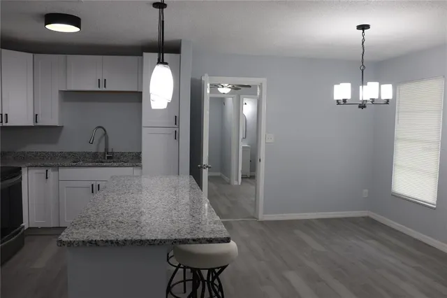 a kitchen with kitchen island granite countertop a sink cabinets and chandelier