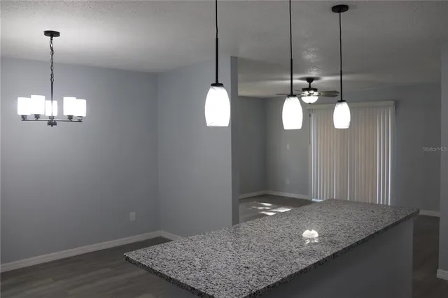 a view of a room with a chandelier fan and wooden floor
