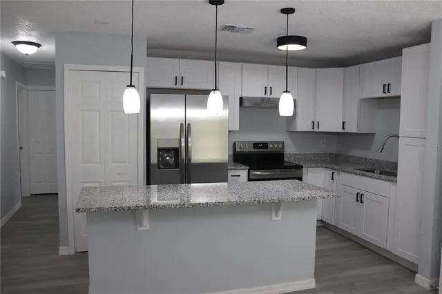 a kitchen with stainless steel appliances granite countertop a sink a stove and a refrigerator