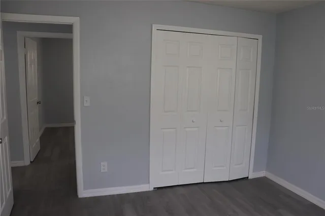 an empty room with wooden floor and closet area