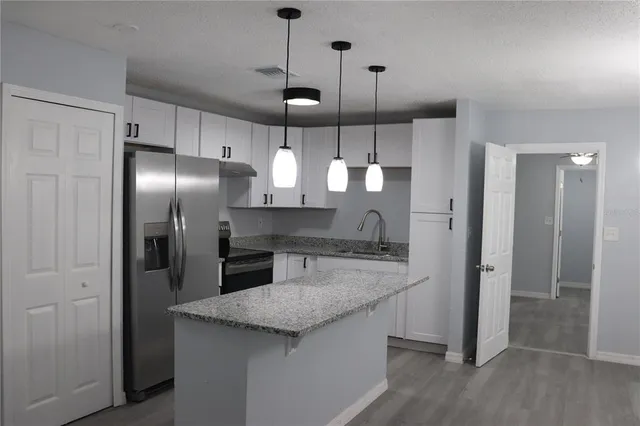 a kitchen with stainless steel appliances granite countertop a refrigerator a sink and a stove