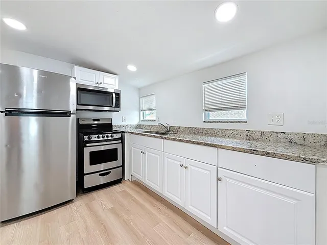 a kitchen with granite countertop a refrigerator stove and microwave