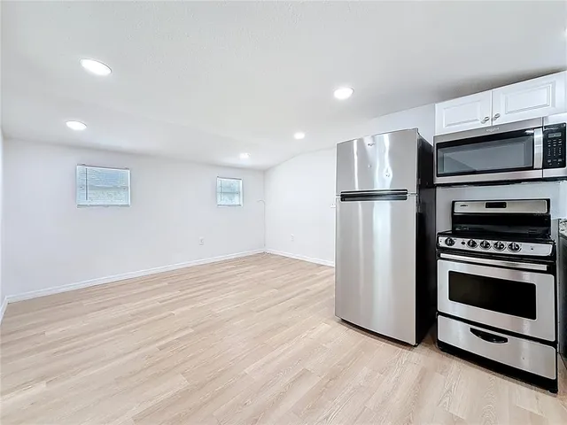 a view of kitchen with stainless steel appliances kitchen island wooden floor and cabinets